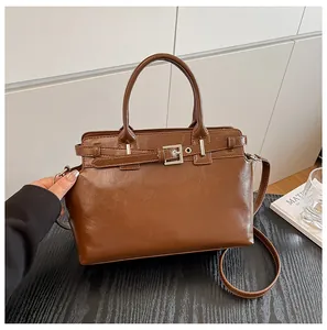 Gros plan d'un sac à main vintage marron avec boucle décorative sur surface sombre