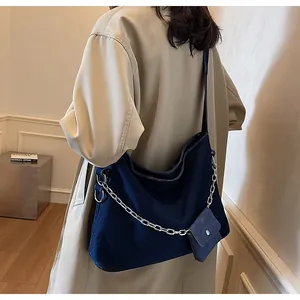 Detail of dark blue denim tote bag with wide strap, silver chain, and mini coin purse