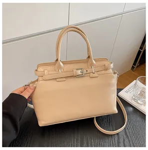 Gros plan d'un petit sac carré en cuir beige avec boucles argentées sur bois