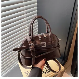 Detail of vintage brown PU leather handbag with shiny oil finish and silver buckles