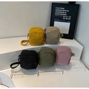 Detailansicht der Mini-Umhängetaschen aus Nylon in fünf Farben auf weißem Ausstellungsstand