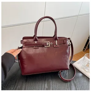 Détail du sac à main en cuir bordeaux montrant la boucle en métal et l'anse