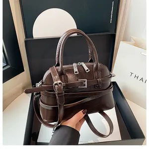Detail of dark brown glossy patent leather handbag with dual handles and silver hardware