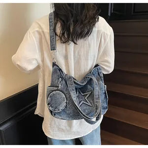 Detailansicht einer blauen Denim-Hobo-Tasche mit Stern-Patch und kleinem Münztäschchen