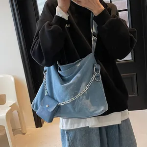 Blue denim hobo tote bag with silver chain and small pouch on a female model