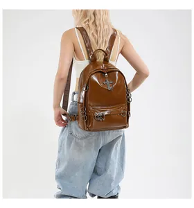 Détail d'un sac à dos en cuir marron brillant avec anneaux en métal et pendentif croix