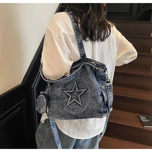 Detail der blauen Denim-Tasche mit Stern-Patch und kleinem runden Münzfach-Anhänger
