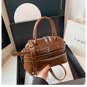 Detail of caramel brown glossy handbag with silver metal buckle in a luxury gift box