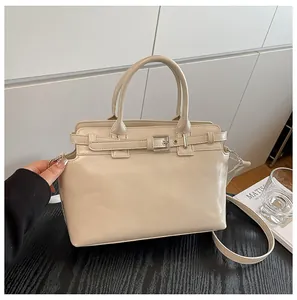 Détail d'un sac à main en cuir crème avec double poignées et boucle en métal