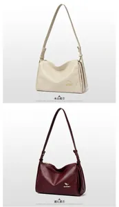 Close-up of pebble leather texture on cream white and wine red Boston bags with metal logo