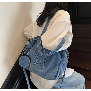 Detail der blauen Denim-Tragetasche mit Stern-Stickerei und kleinem runden Münzbeutel-Anhänger