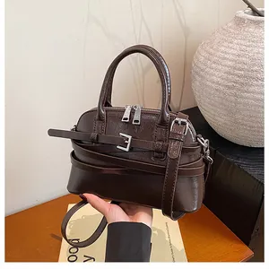 Detailed close-up of dark brown glossy leather crossbody bag with silver hardware