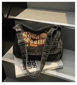 Detail of washed black denim tote bag with colorful embroidery and metal buckle adjuster