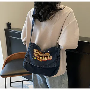 Detail of dark blue denim crossbody bag featuring colorful 'Lucky' embroidery on flap