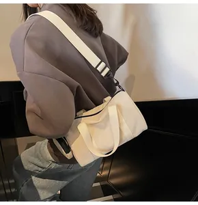 Détail d'un sac Boston en toile crème avec bandoulière réglable et design cylindrique