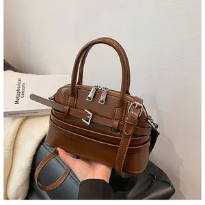 Detailed shot of dark brown shell bag featuring decorative straps and silver buckles