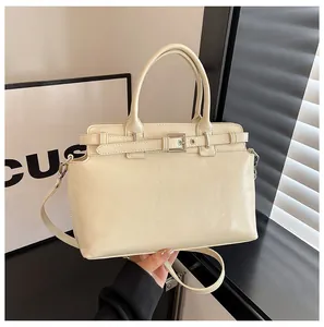 Détail du sac carré en cuir crème avec boucle décorative et doubles poignées