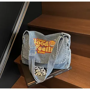 Detailed close-up of blue denim tote bag with Lookin' Good Feeling Good embroidery