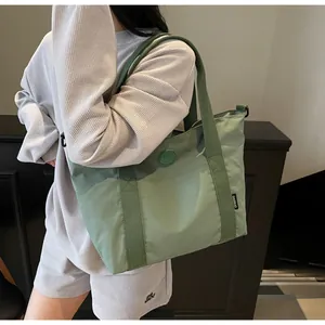 Détail du grand sac cabas vert clair avec logo circulaire et poignées robustes
