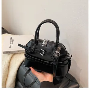Detail view of the black glossy leather small square bag with dual zippers and buckles