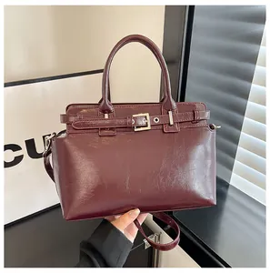 Détail du sac à main en cuir verni bordeaux avec boucle argentée et bandoulière amovible
