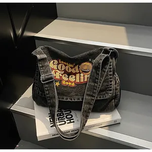Detail showing colorful embroidery on charcoal denim canvas tote with metal buckle