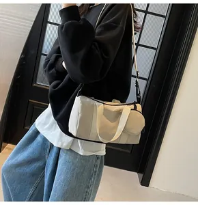 Femme portant un grand sac polochon en toile blanc cassé avec bandoulière et pochette
