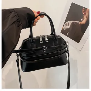 Close-up of black shell bag showing silver hardware, dual zippers and belt buckle detail