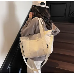 Détail d'un grand sac cabas en nylon beige avec doubles poignées et bandoulière réglable