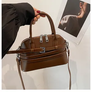 Detail of dark brown polished leather shell bag with decorative buckles and silver hardware