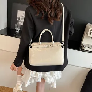 Sac carré beige chic pour femme avec poignée supérieure et fini brillant sur un mannequin