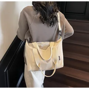 Gros plan d'un grand sac cabas beige en toile avec logo latéral et bandoulière réglable