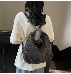 Detail of vintage washed black denim shoulder bag with frayed letter patches and street style