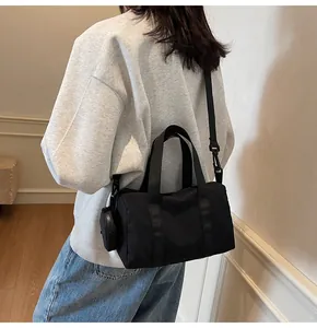 Détail du sac polochon noir en toile avec bandoulière amovible et petite pochette