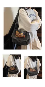 Detail view of large grey denim tote bag with retro embroidery patches on wooden stairs