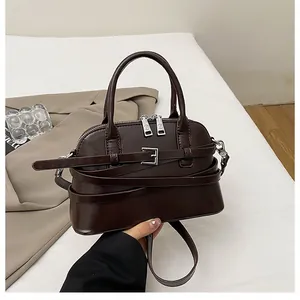 Detail view of a vintage dark brown leather crossbody bag with adjustable strap and handles
