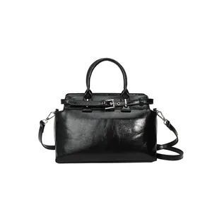 Petit sac carré noir brillant avec boucle argentée et bandoulière pour un look moderne