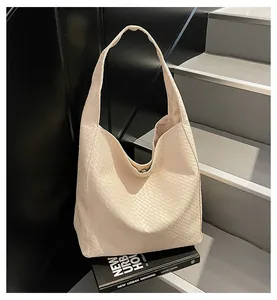 Detail shot of cream woven tote bag with cross-stitch texture and metal clasp closure