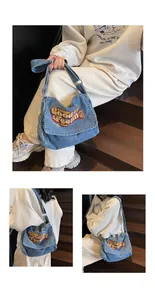 Detail of light blue denim messenger bag with colorful Lookin Good embroidery text