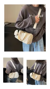 Détail du sac cylindrique en toile blanc cassé avec bandoulière et mini porte-monnaie