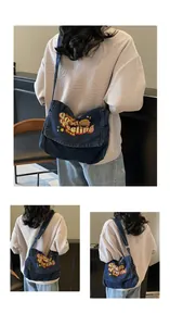 Detail of blue denim tote bag featuring colorful embroidery and adjustable shoulder strap