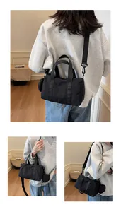 Détail du sac Boston en nylon noir avec un mini porte-monnaie rond et des sangles