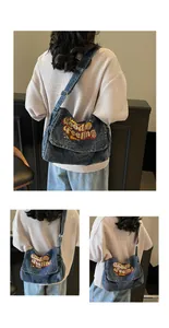 Detail of blue denim messenger bag featuring vintage 'Good Feeling' embroidery and adjustable strap