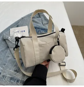 Détail du sac cylindrique en nylon blanc cassé avec zip noir et petit pendentif
