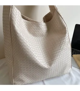 Detail shot of the beige woven hobo bag with wide shoulder strap in a daily office setting