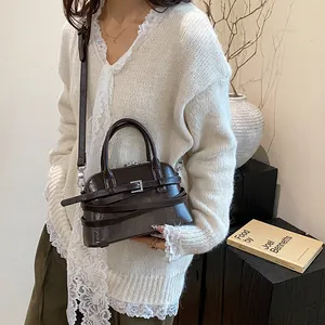 Chic dark brown leather shell bag with vintage buckles and adjustable shoulder strap