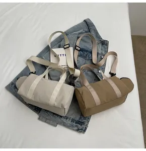 Vue de dessus des sacs bowling en toile crème et kaki avec bandoulière sur veste en jean