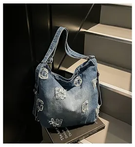 Close-up of vintage blue denim tote bag with frayed G letter patterns and metal buckle