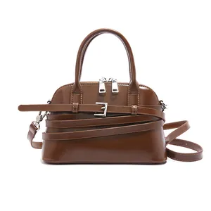 Classic dark brown shell-shaped crossbody bag with decorative strap and silver hardware