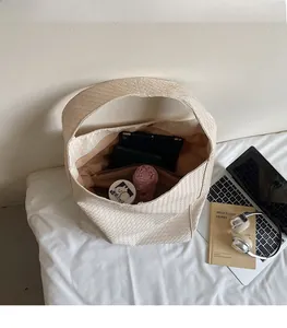 Spacious interior of beige woven tote bag holding a tablet, umbrella, and cosmetics